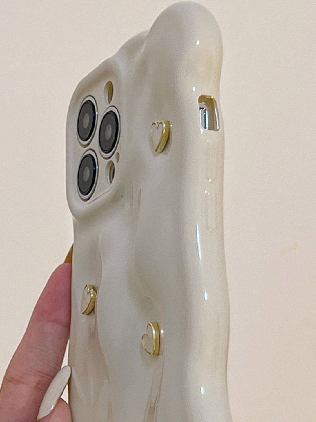 Elegant TALISHKO phone case with 3D heart accents, held in hand, showcasing a unique design.