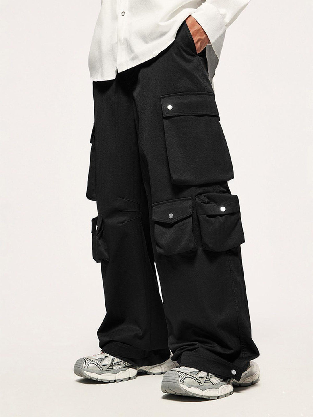 Model in TALISHKO's black cargo pants with multiple pockets, paired with white top and sneakers.