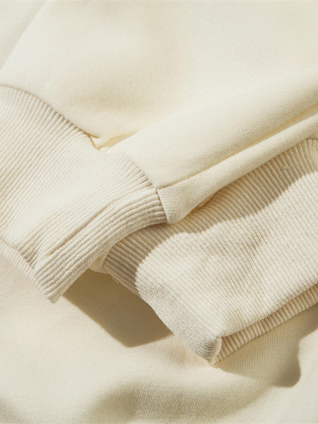 Intricate detail of TALISHKO's pullover hoodie sleeve showcasing soft beige ribbed texture.
