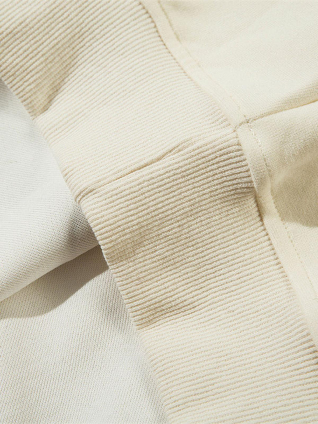 Detailed fabric and stitching on TALISHKO's beige pullover hoodie, highlighting ribbed texture.