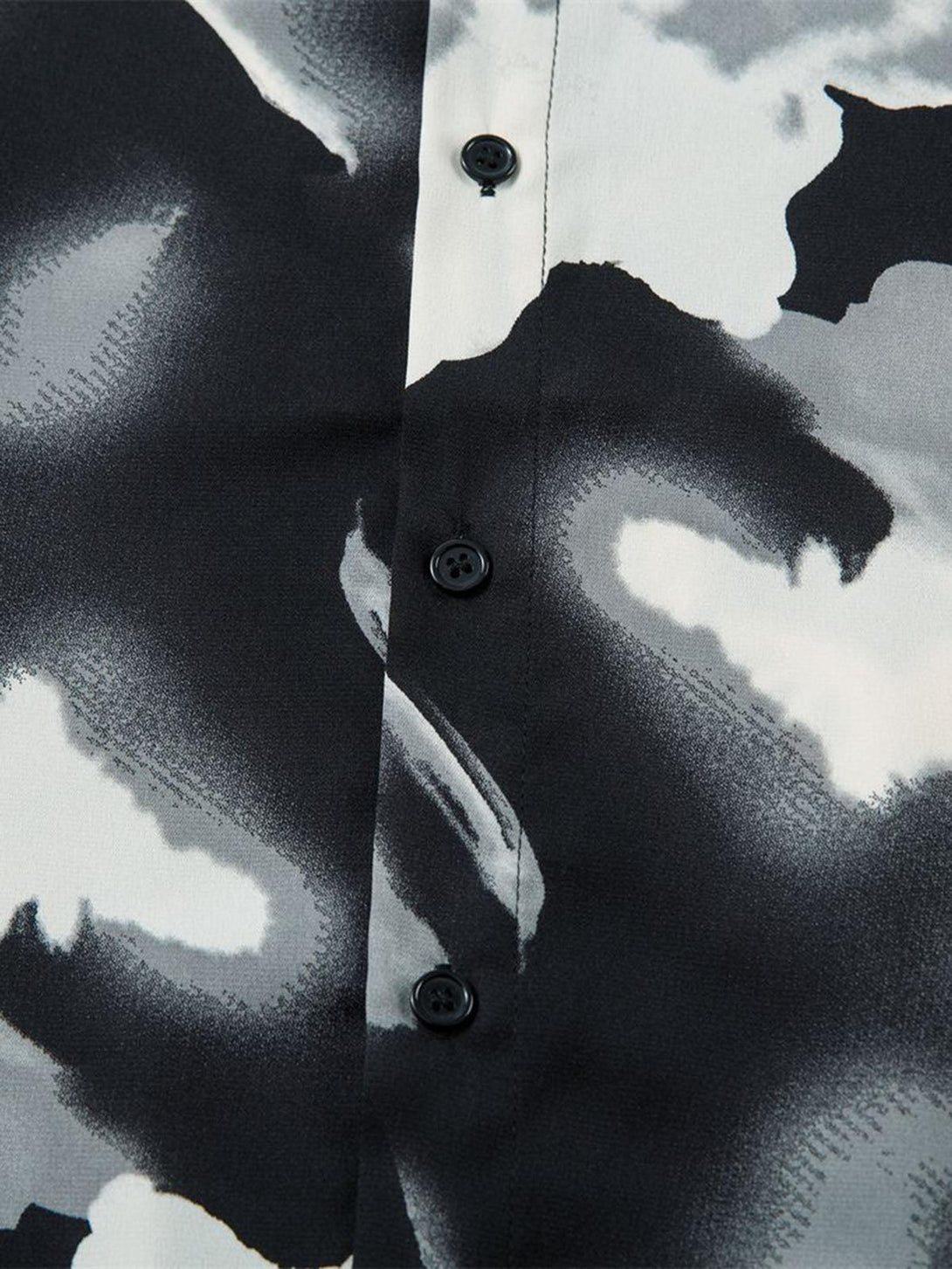 A detailed view of TALISHKO's abstract tie-dye shirt, highlighting its bold monochrome pattern.