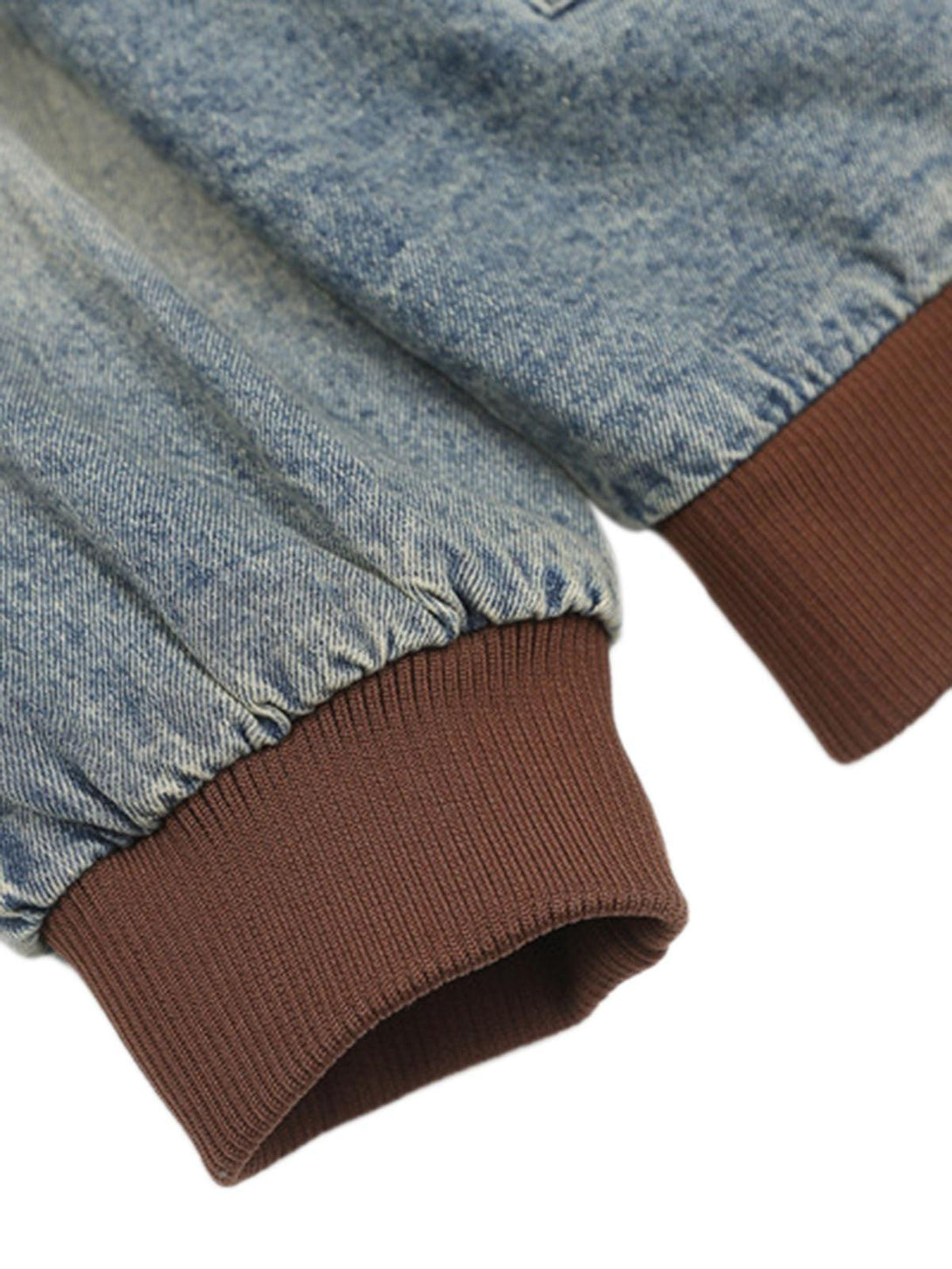 Focusing on the elastic cuffs of the TALISHKO denim bomber jacket with quilted detailing.