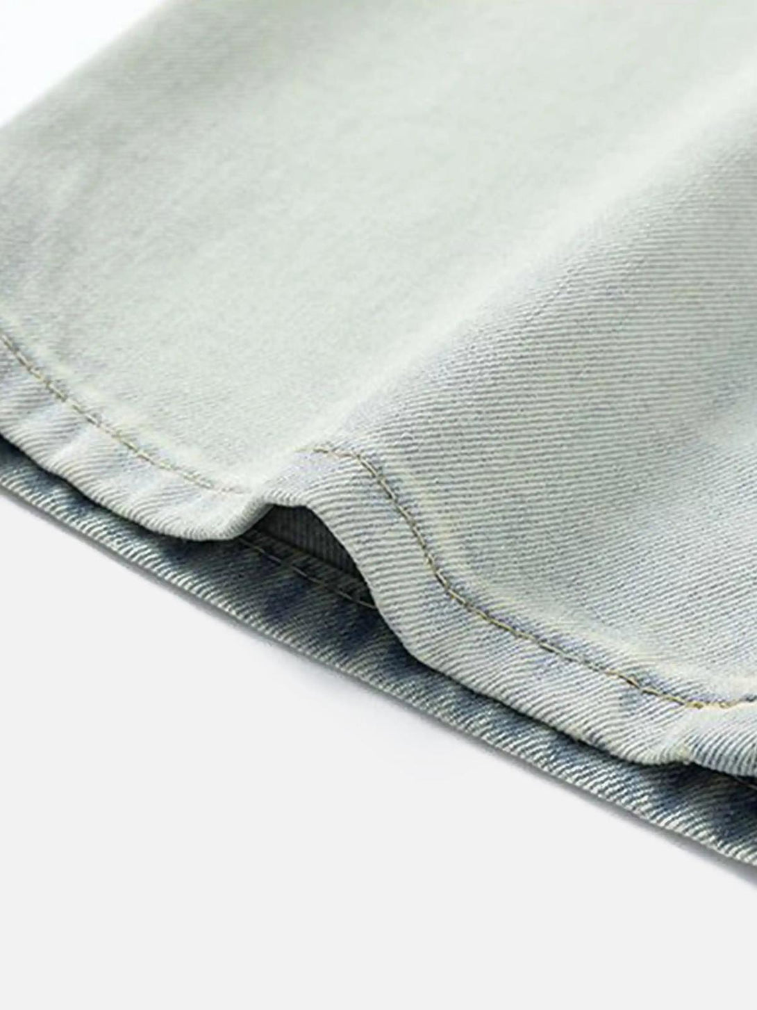 Intricate look at TALISHKO jeans' hem, showcasing the vintage gradient bleach wash texture.