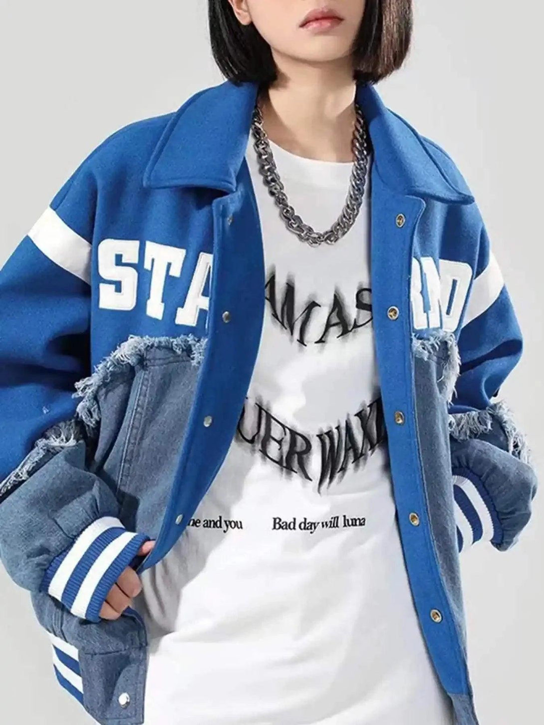 Model wearing TALISHKO's blue denim spliced baseball jacket with bold lettering and frayed edges.