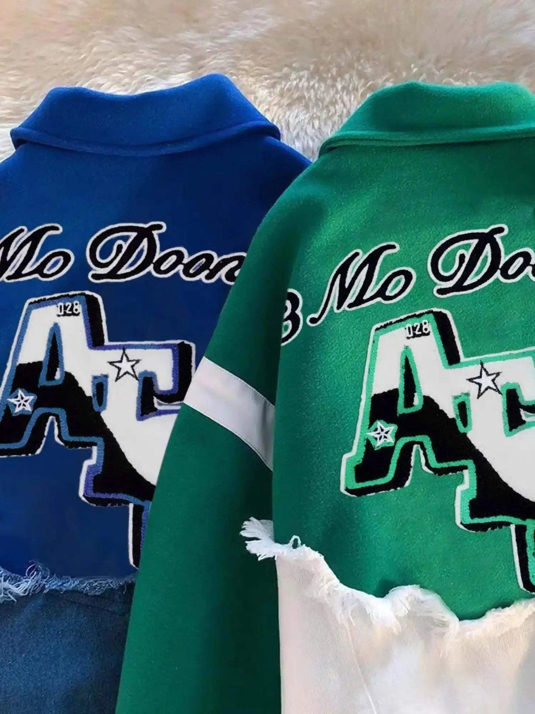 Back view of TALISHKO's blue and green baseball jackets, highlighting bold lettering and frayed edges.