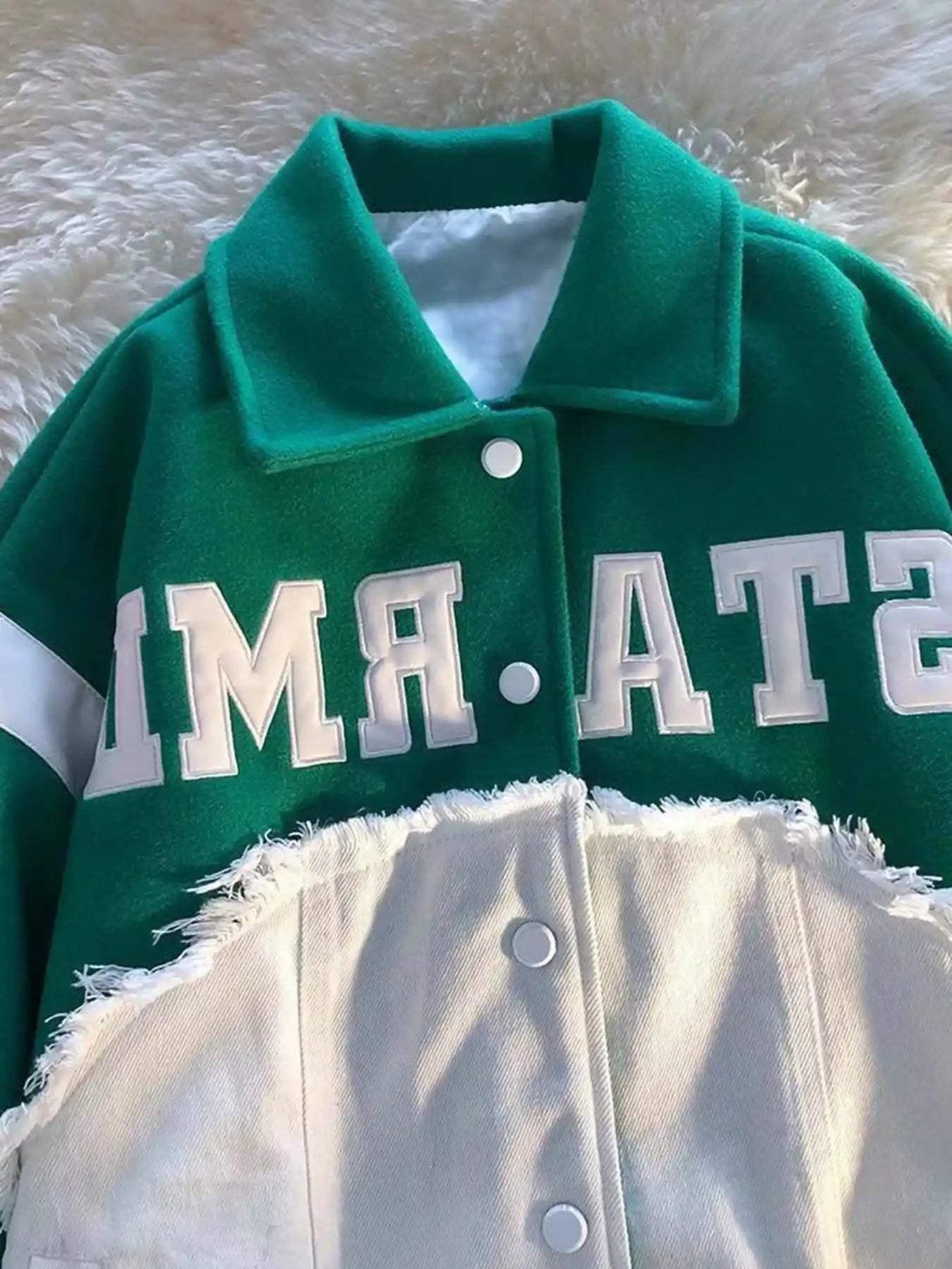 Focusing on TALISHKO's green baseball jacket, highlighting frayed edges and bold lettering.