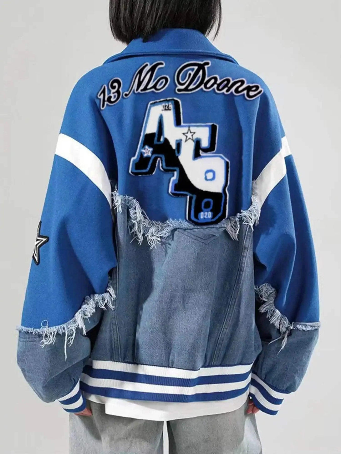 Back view of TALISHKO's blue denim splicing baseball jacket with frayed details and bold graphics.