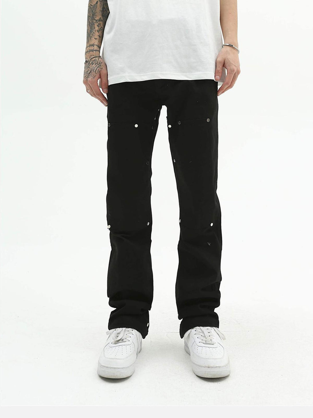 Front view of black jeans with metal detailing, paired with white sneakers by TALISHKO.