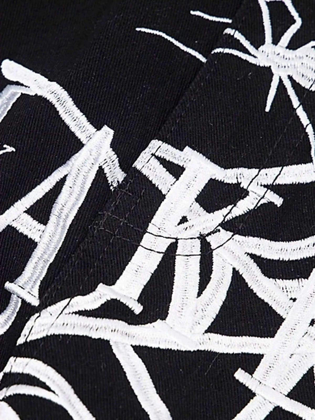 Intricate embroidery detail on TALISHKO jeans, highlighting unique spider web design.
