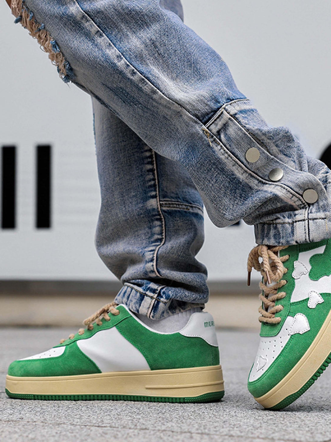 TALISHKO green and white retro sneakers paired with distressed jeans, side view.