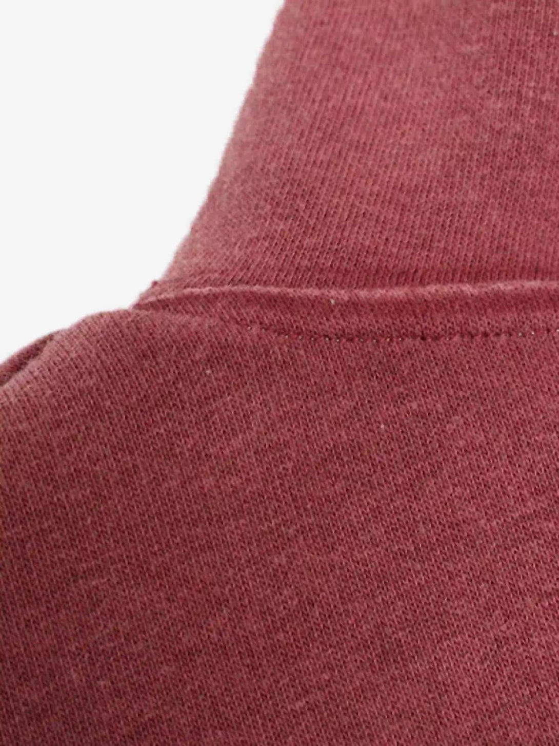 A close-up of the shoulder stitching on a red TALISHKO hoodie, showcasing its soft texture.