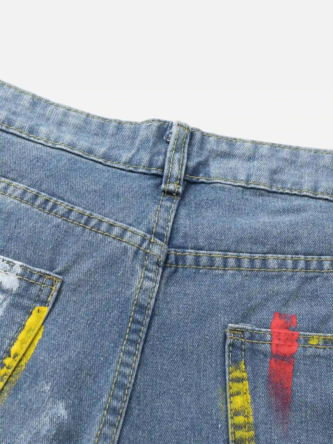 Paint-splattered pocket detail on TALISHKO jeans, highlighted by vibrant yellow and red accents.