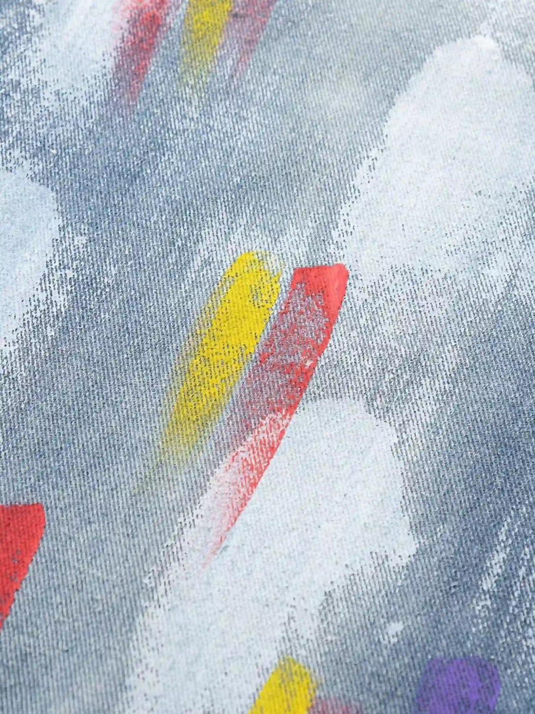Zoomed-in texture of TALISHKO jeans showcasing colorful paint strokes and artistic flair.