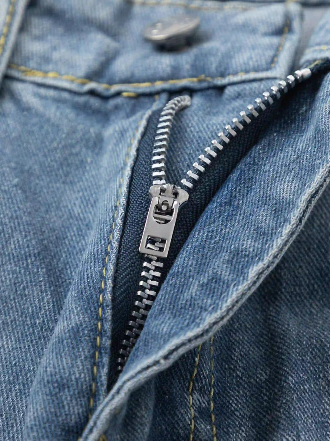 A detailed look at TALISHKO jeans' sturdy zipper and stitching on blue denim fabric.