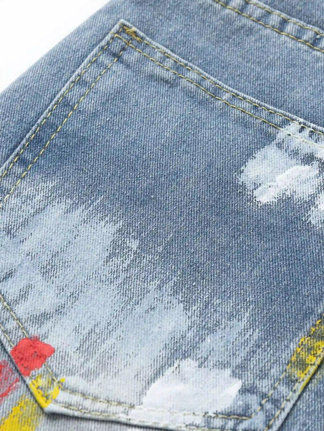 A close-up of TALISHKO jeans, featuring artistic paint splatters on the back pocket.