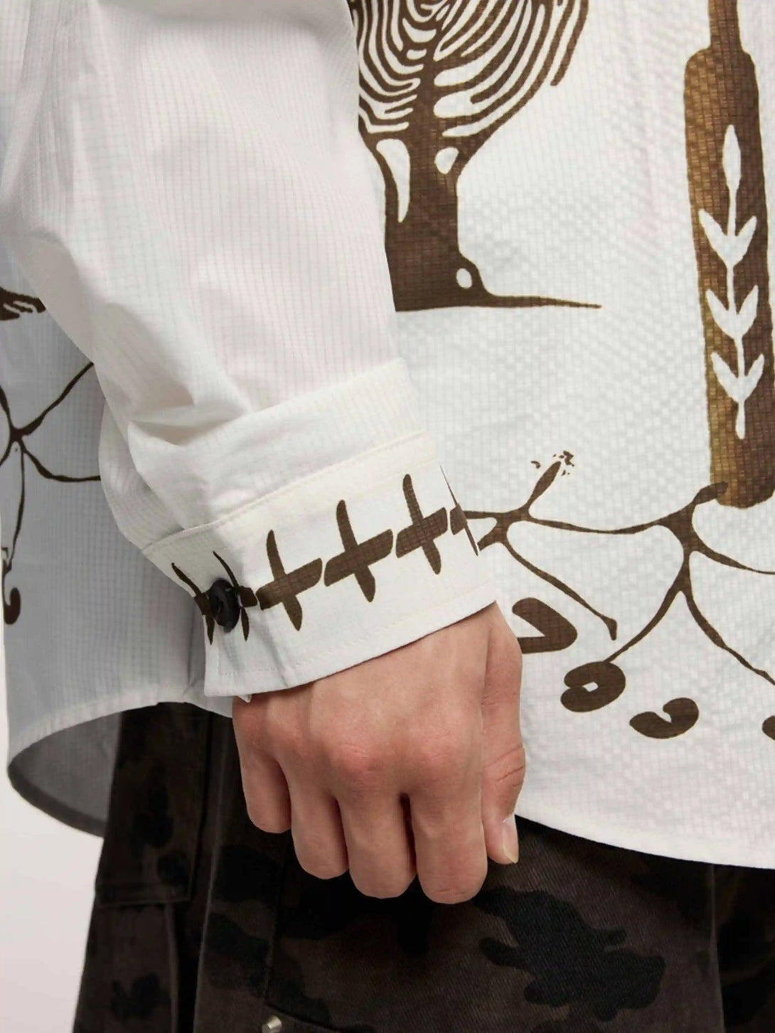 Close-up of TALISHKO shirt sleeve with intricate Mayan-inspired patterns and button detail.