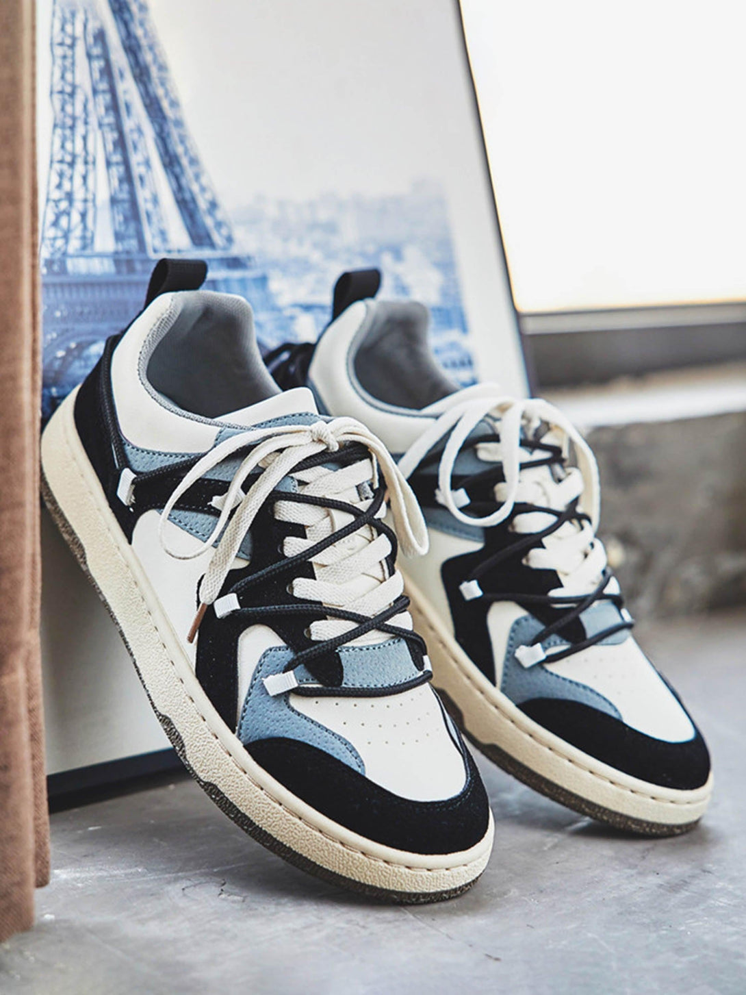 TALISHKO skateboard shoes in white and blue, set against a backdrop of an artistic cityscape.
