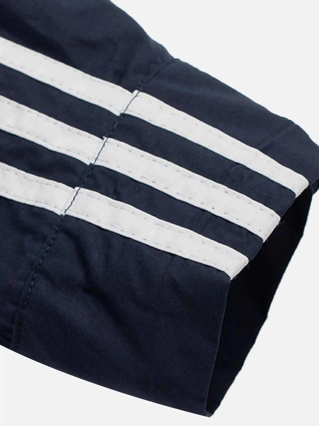 Detailed fabric and stitching on TALISHKO's navy long-sleeved shirt, highlighting sporty stripes.