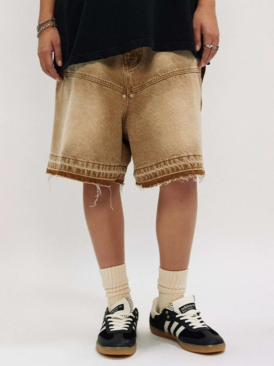 A model wears TALISHKO's retro distressed denim shorts, paired with sneakers for a casual look.