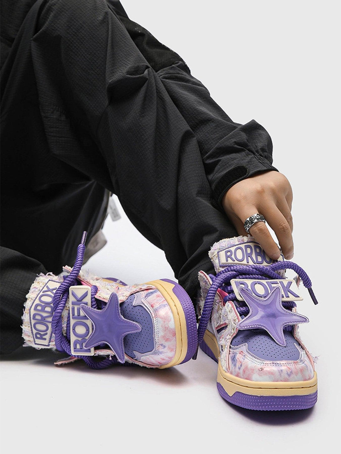 TALISHKO sneakers with purple star accents and multicolor patterns, paired with black pants.
