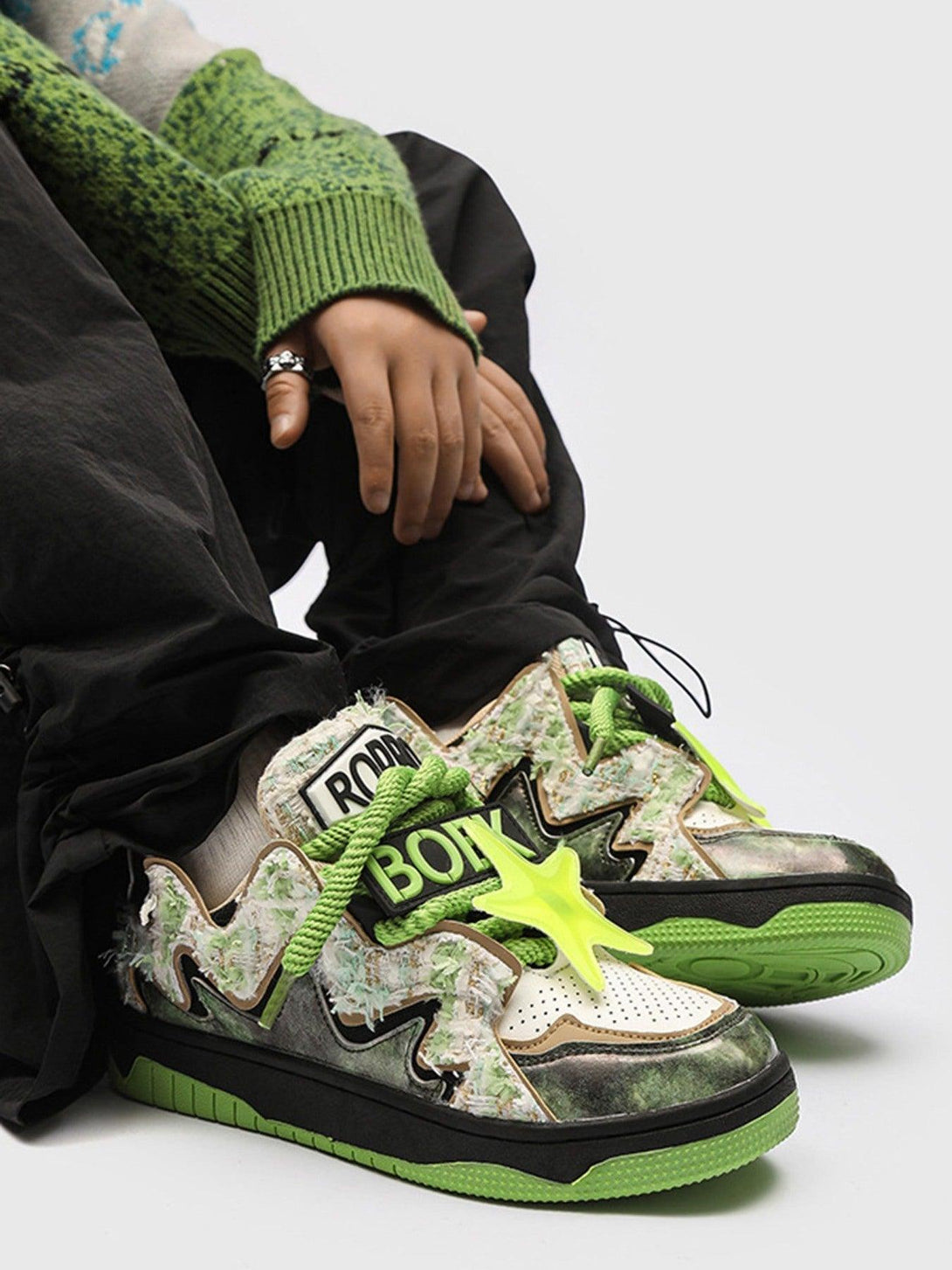 TALISHKO high street sneakers featuring green accents and star details, styled with cozy knitwear.