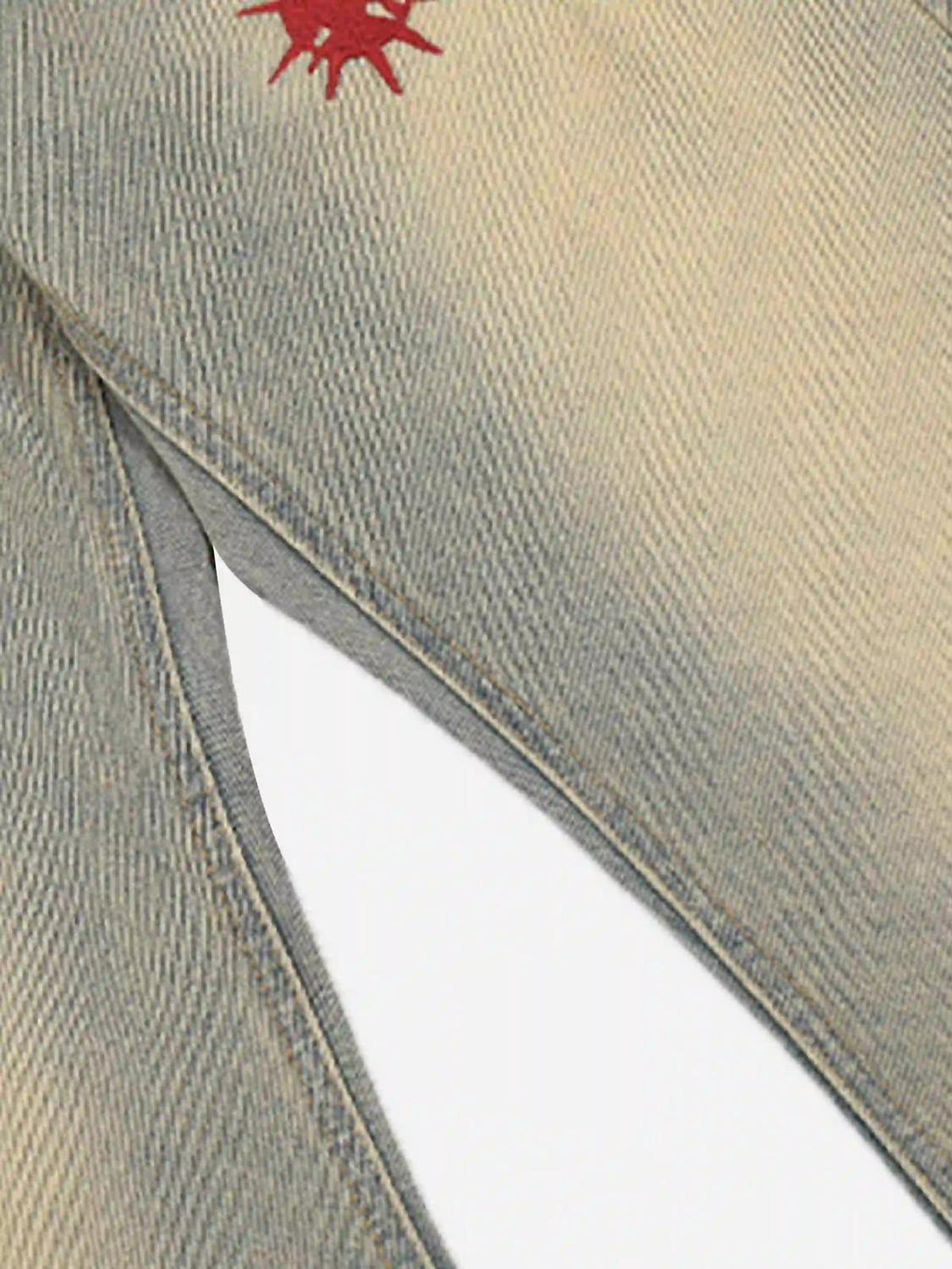 A detailed view of TALISHKO jeans' fabric with red embroidery, showcasing retro hip-hop flair.