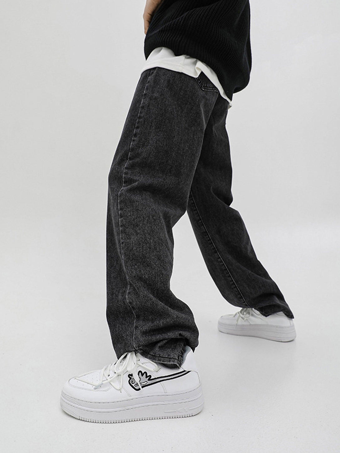 Model showcasing TALISHKO white sneakers with a playful design, paired with dark jeans.