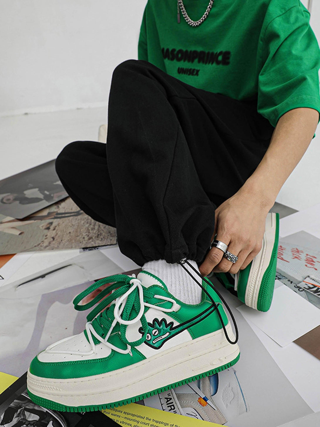 Model wearing green TALISHKO hip-hop sneakers with monster graphic, styled with casual outfit.