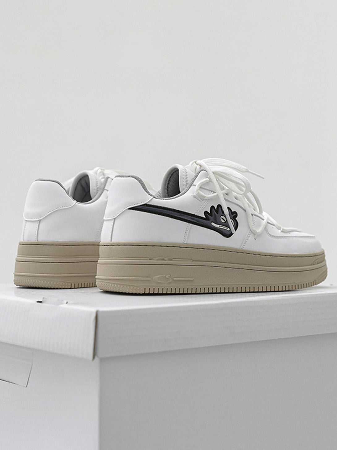 White TALISHKO sneakers with monster graphic and beige soles on a box, casual style.