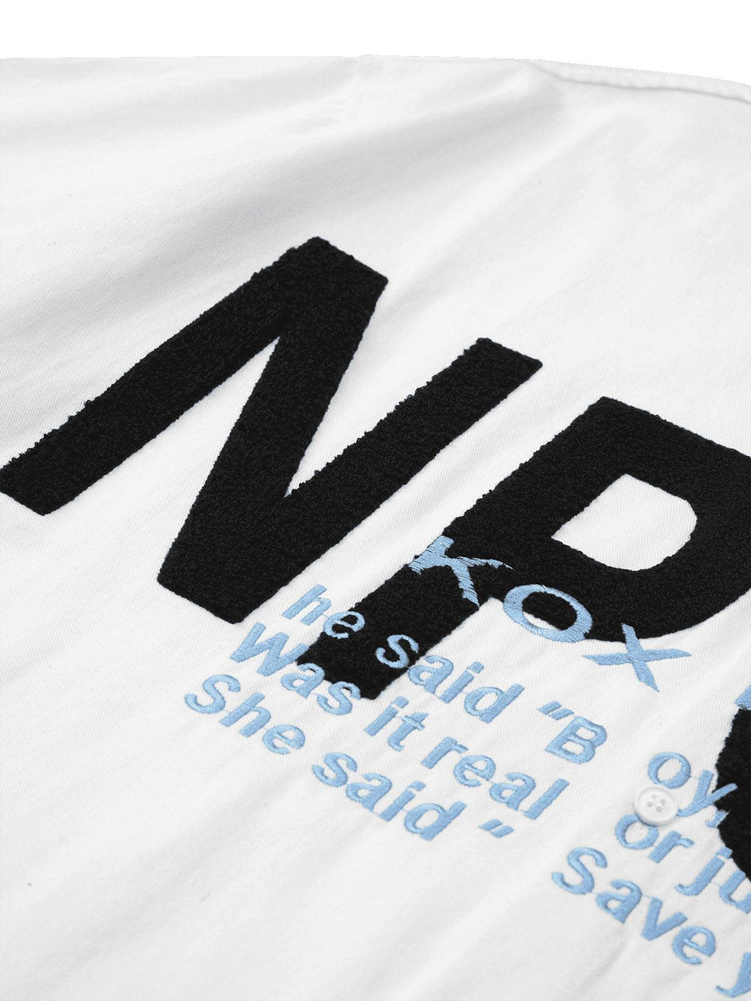 Zoomed-in view of TALISHKO's white shirt featuring bold black and blue embroidered text.