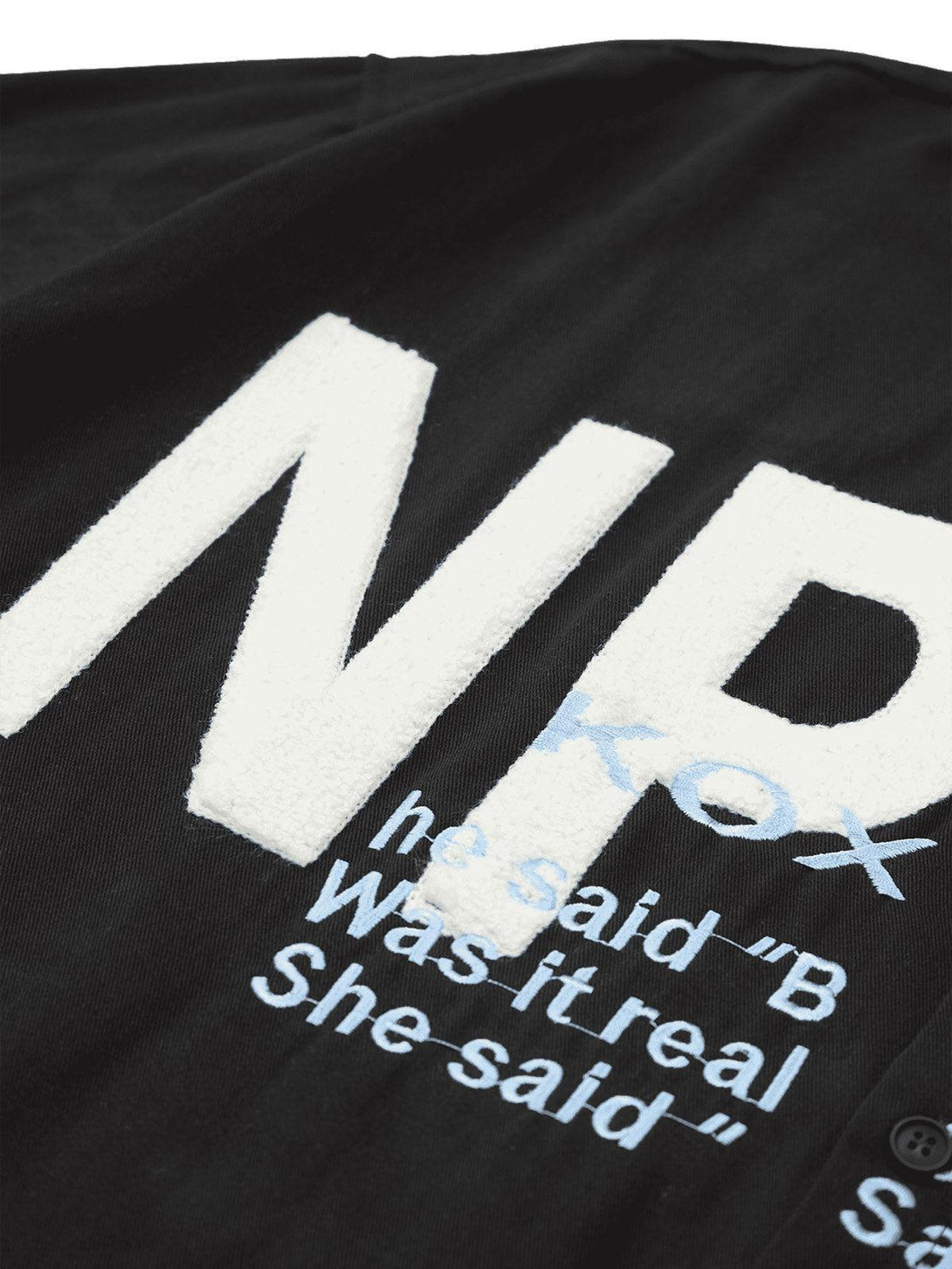 A detailed look at TALISHKO's black shirt with bold, contrasting embroidered letters.