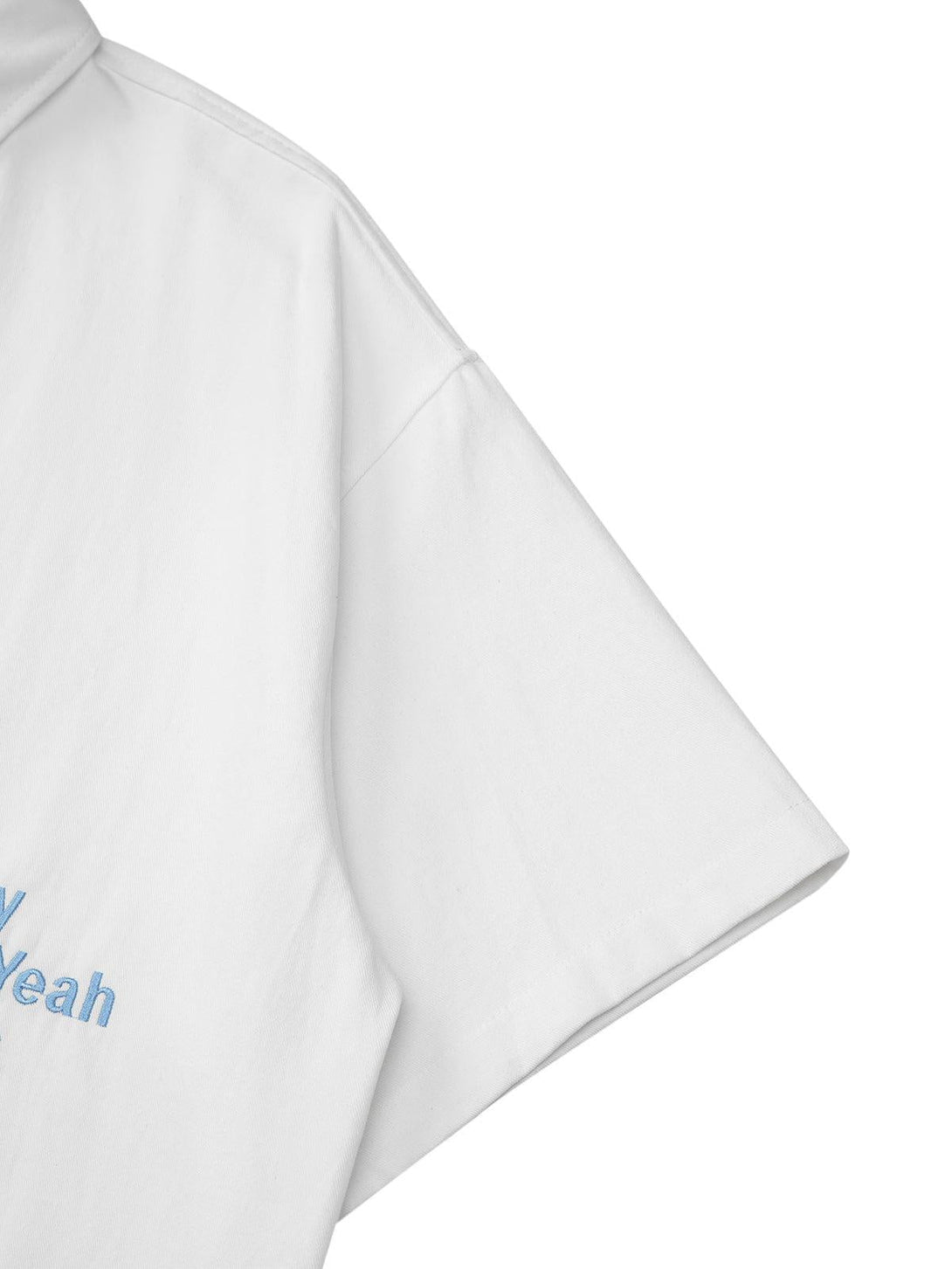 Detailed fabric and stitching of a white TALISHKO shirt with subtle blue embroidery.