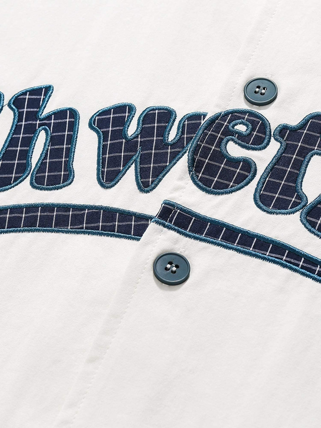 A close-up of TALISHKO's shirt, highlighting retro letter patches and button details.