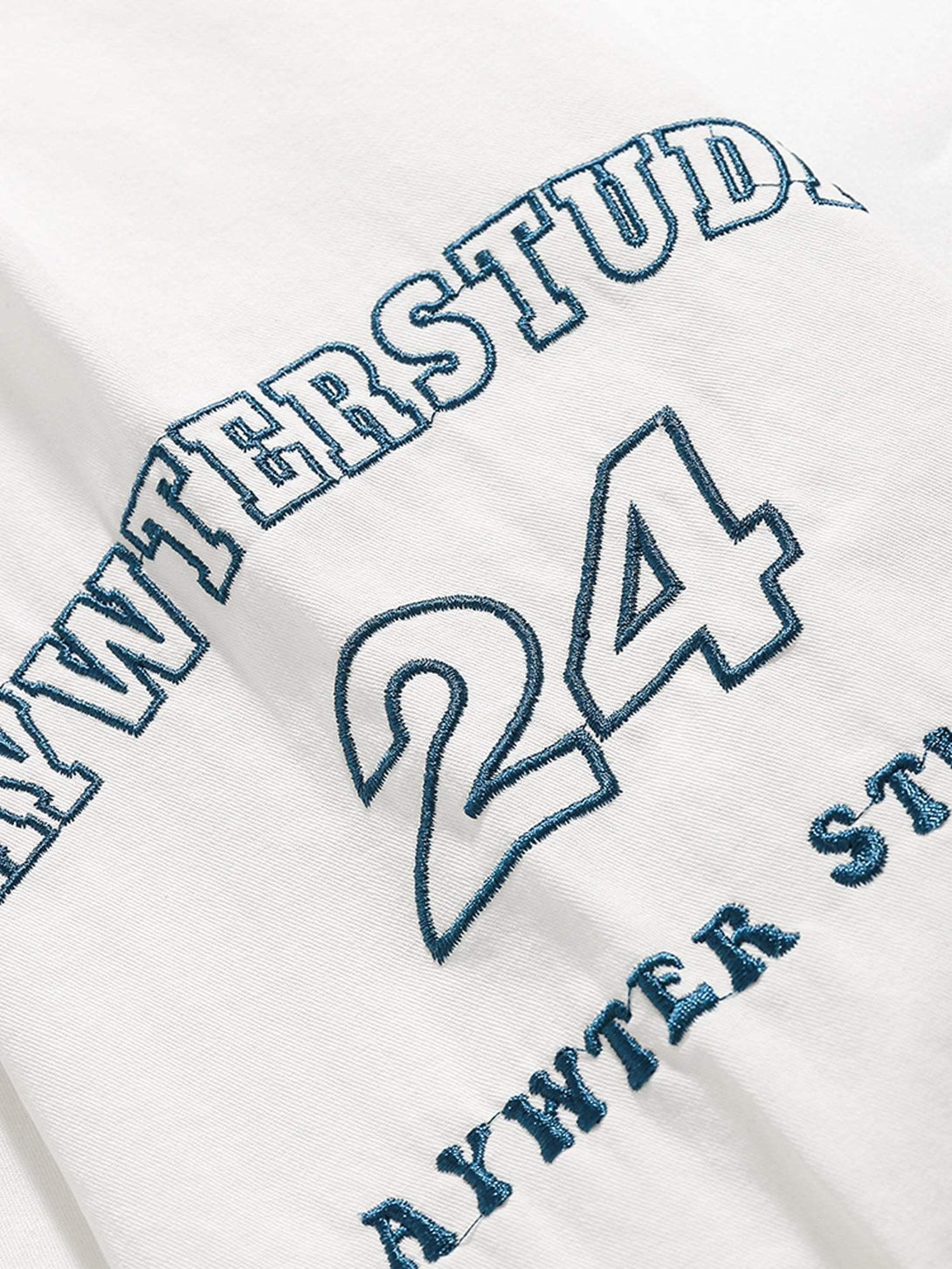 Intricate look at TALISHKO's retro letter patch on a white short-sleeved shirt.