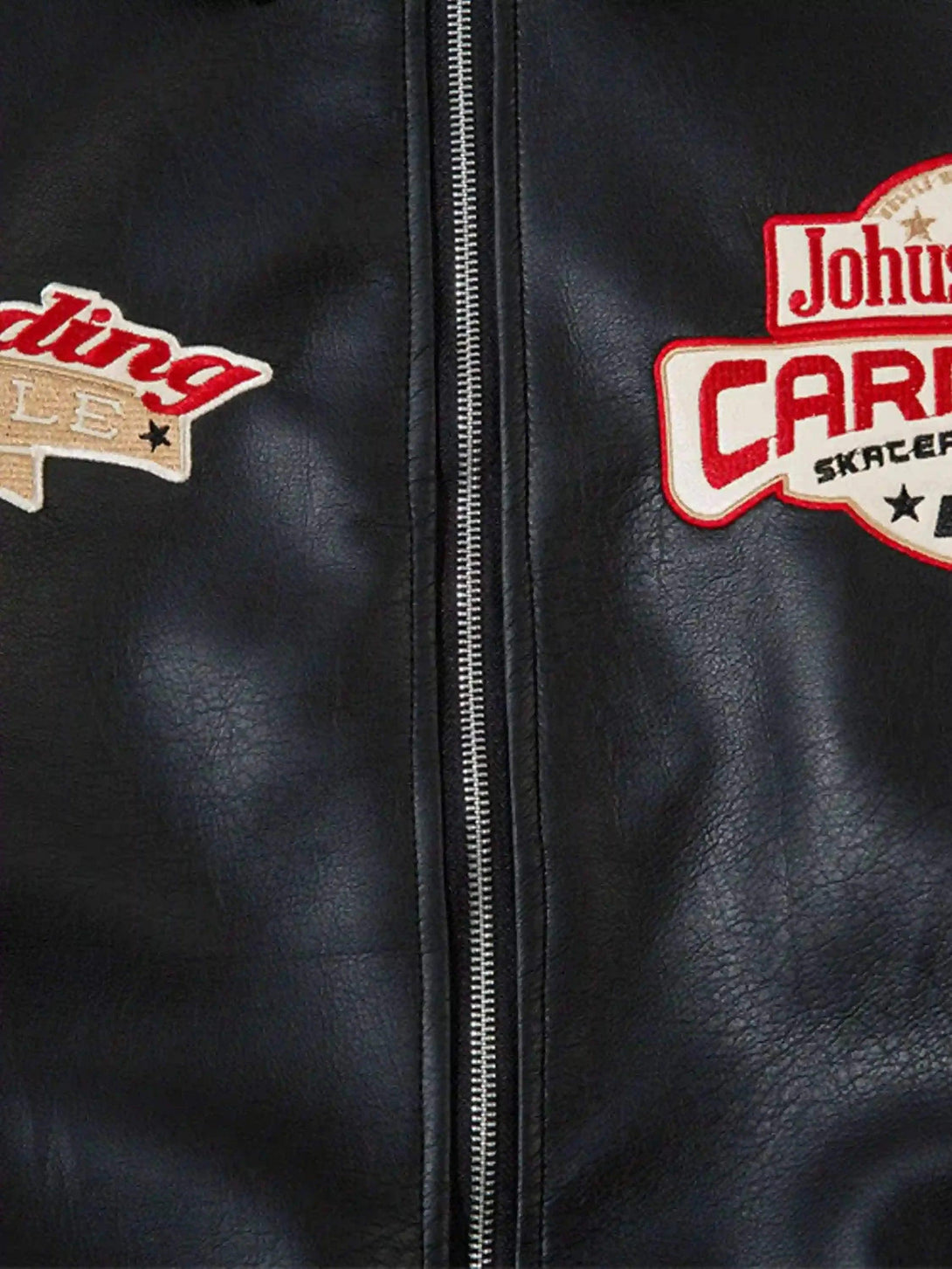 Close-up of TALISHKO's black leather motorcycle jacket featuring retro patches and sleek zipper.