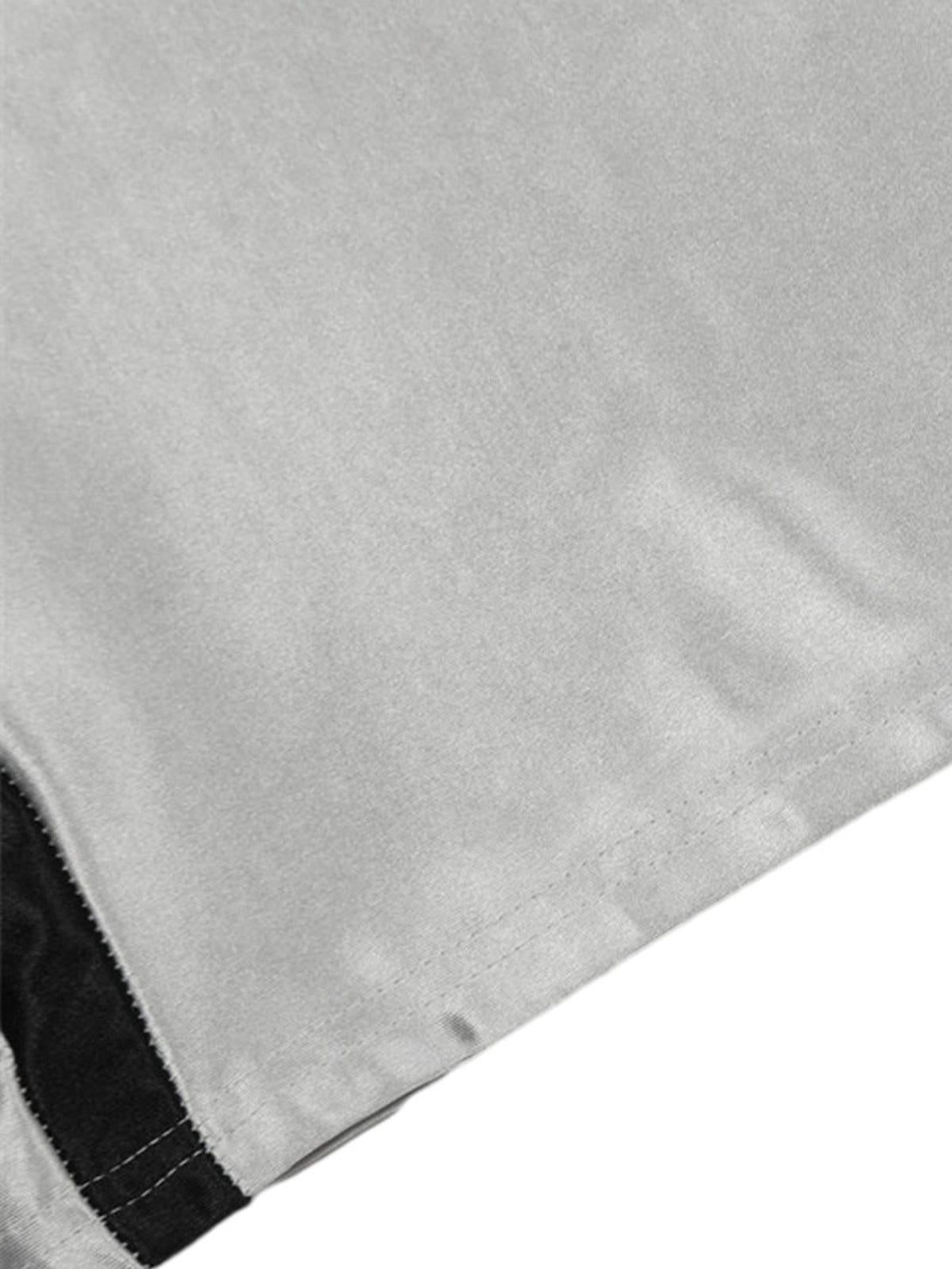 A tight crop highlighting the hem and black patch detail on TALISHKO's silver T-shirt.