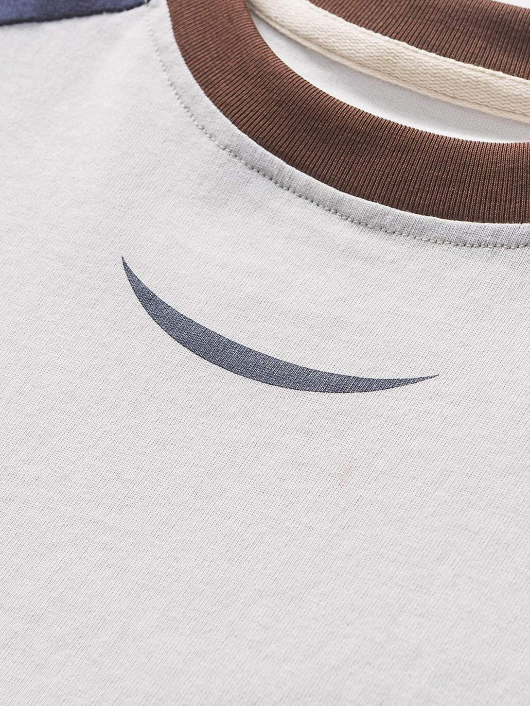 A zoomed-in view of TALISHKO's patchwork T-shirt, highlighting the neckline and subtle design.