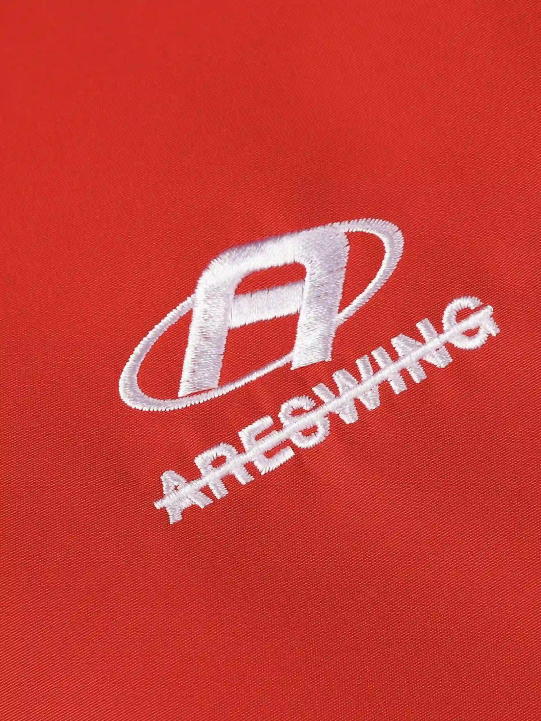 A close-up of the TALISHKO red sports jacket logo, highlighting the intricate white stitching.
