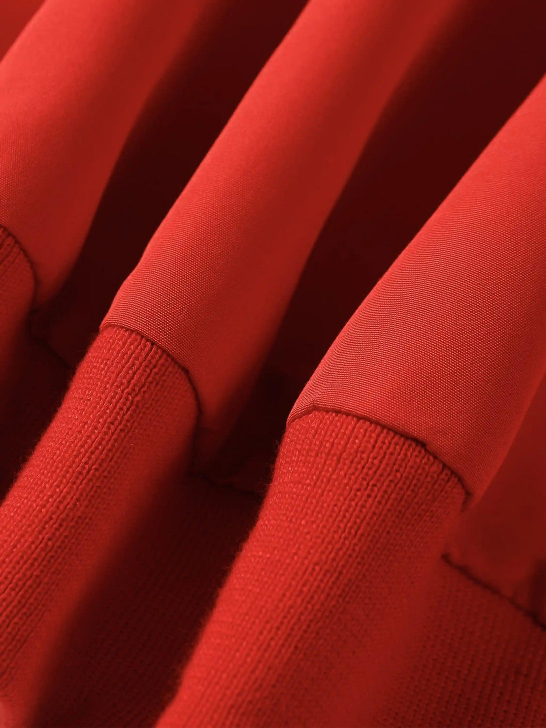 A tight crop highlighting the vibrant red fabric and texture of the TALISHKO sports jacket.