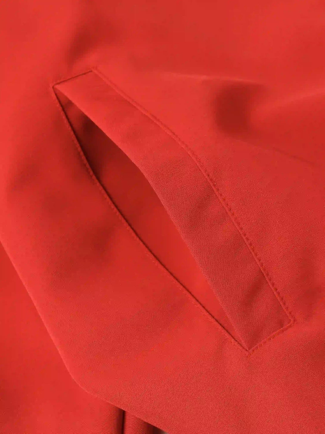 A detailed view of the vibrant red TALISHKO sports jacket pocket, showcasing sleek stitching.