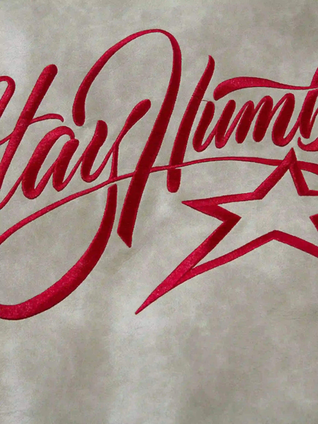 Intricate look at TALISHKO's red "Stay Humble" embroidery on soft motorcycle jacket fabric.