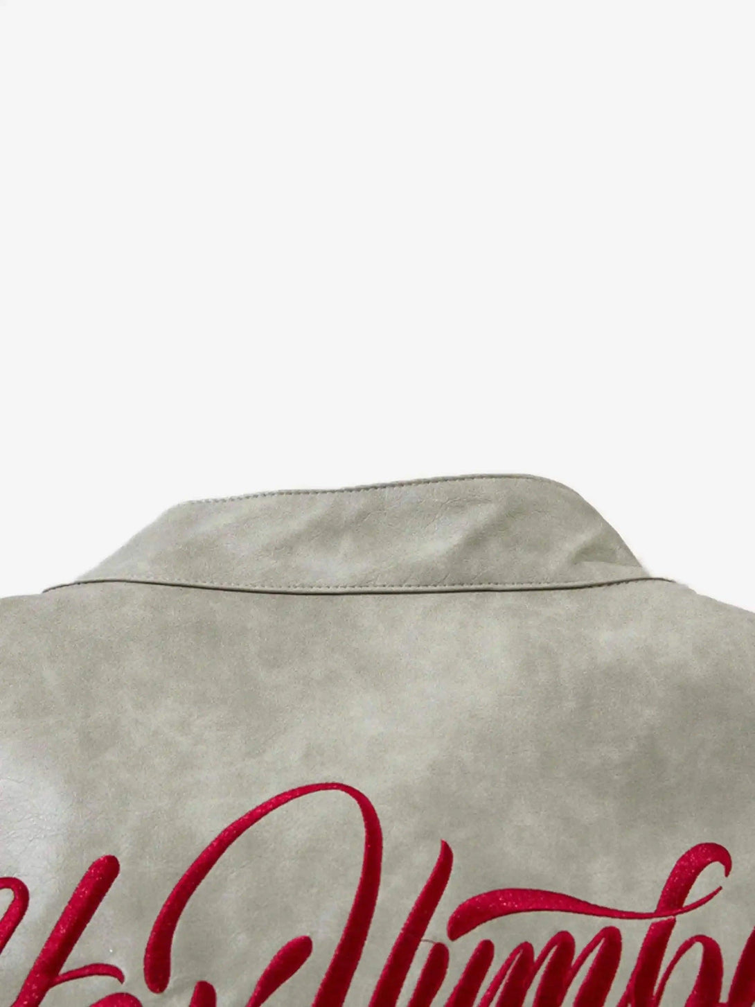 A detailed look at the TALISHKO jacket's collar and red script embroidery on soft fabric.
