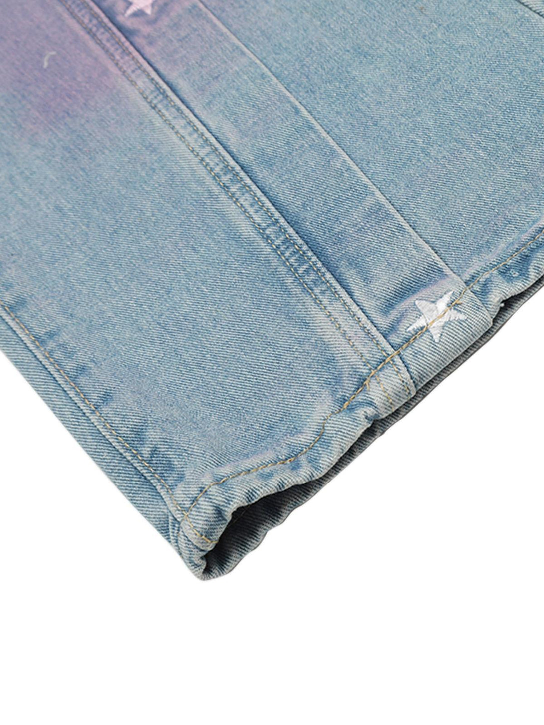 A detailed look at TALISHKO jeans' hem, showcasing star embroidery and spray-painted effects.