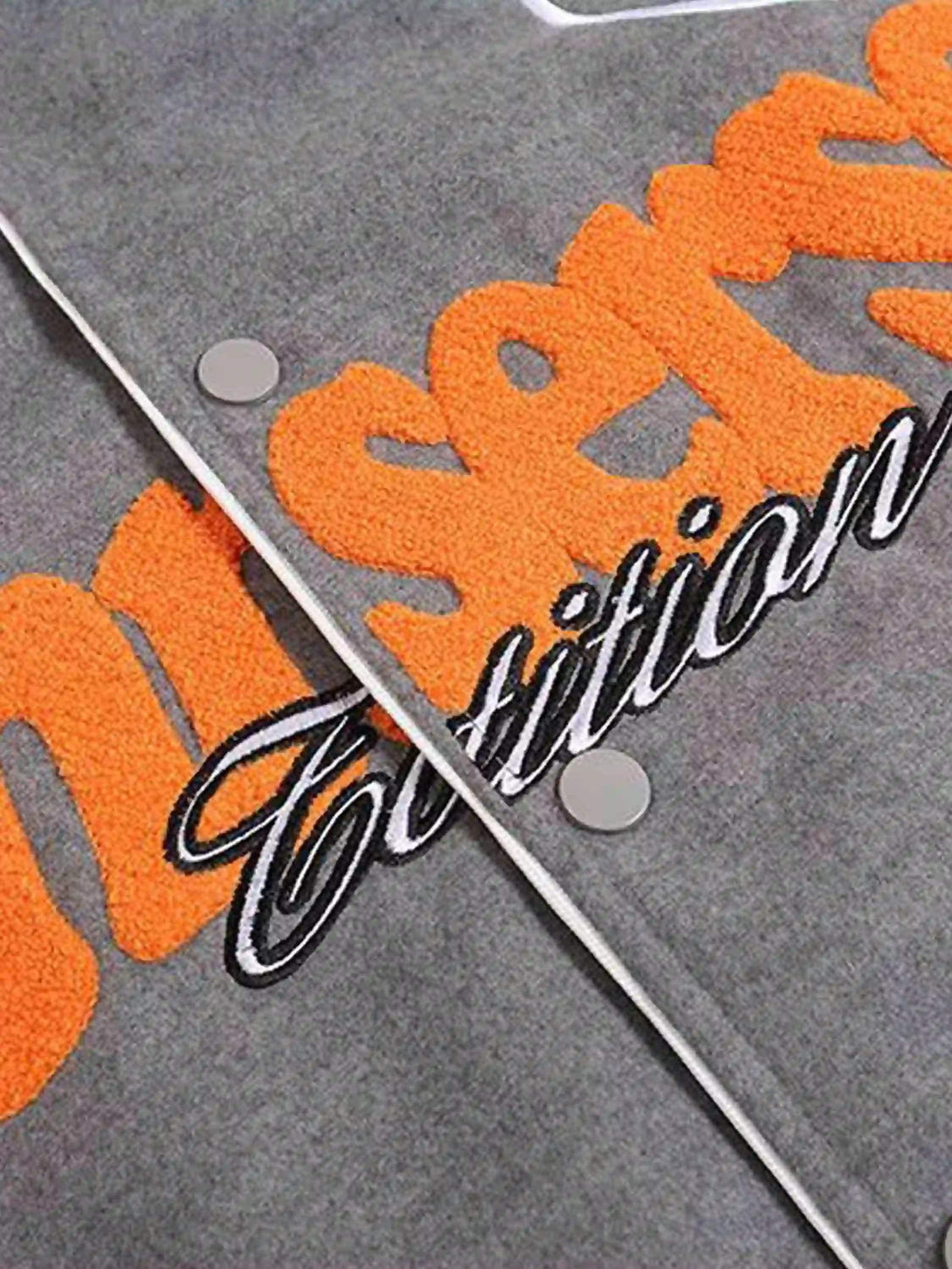 Detailed fabric and stitching on a TALISHKO woolen baseball jacket with orange and black lettering.