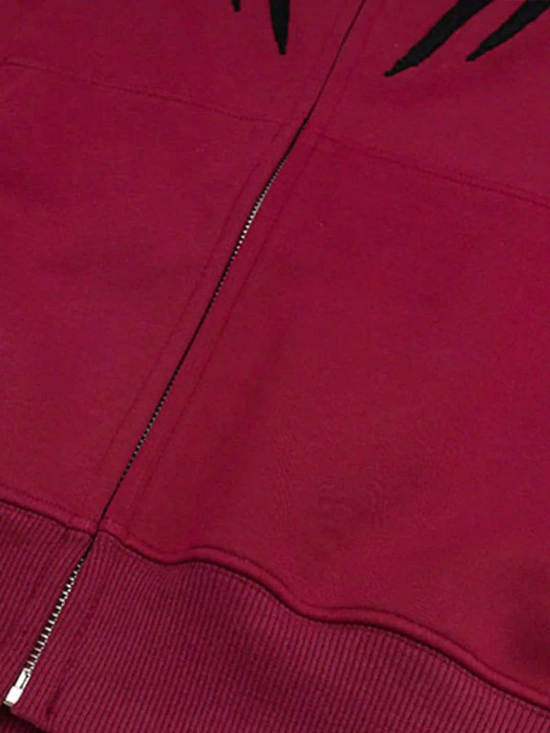 Detailed fabric and stitching of red TALISHKO cardigan hoodie with subtle spider embroidery.