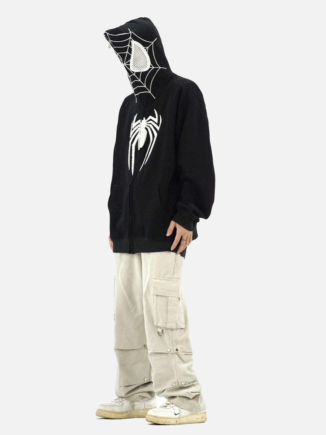 Model wearing a black TALISHKO hoodie with spider web design, paired with beige cargo pants.