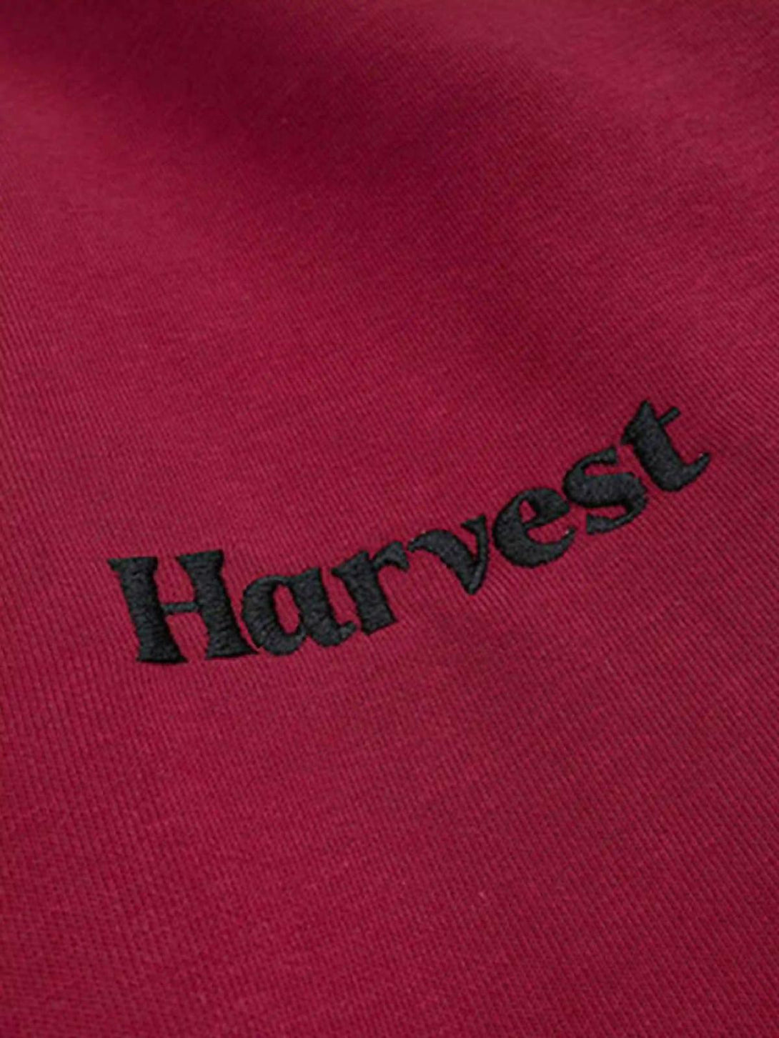 A close-up of red TALISHKO hoodie fabric with "Harvest" embroidery detail.