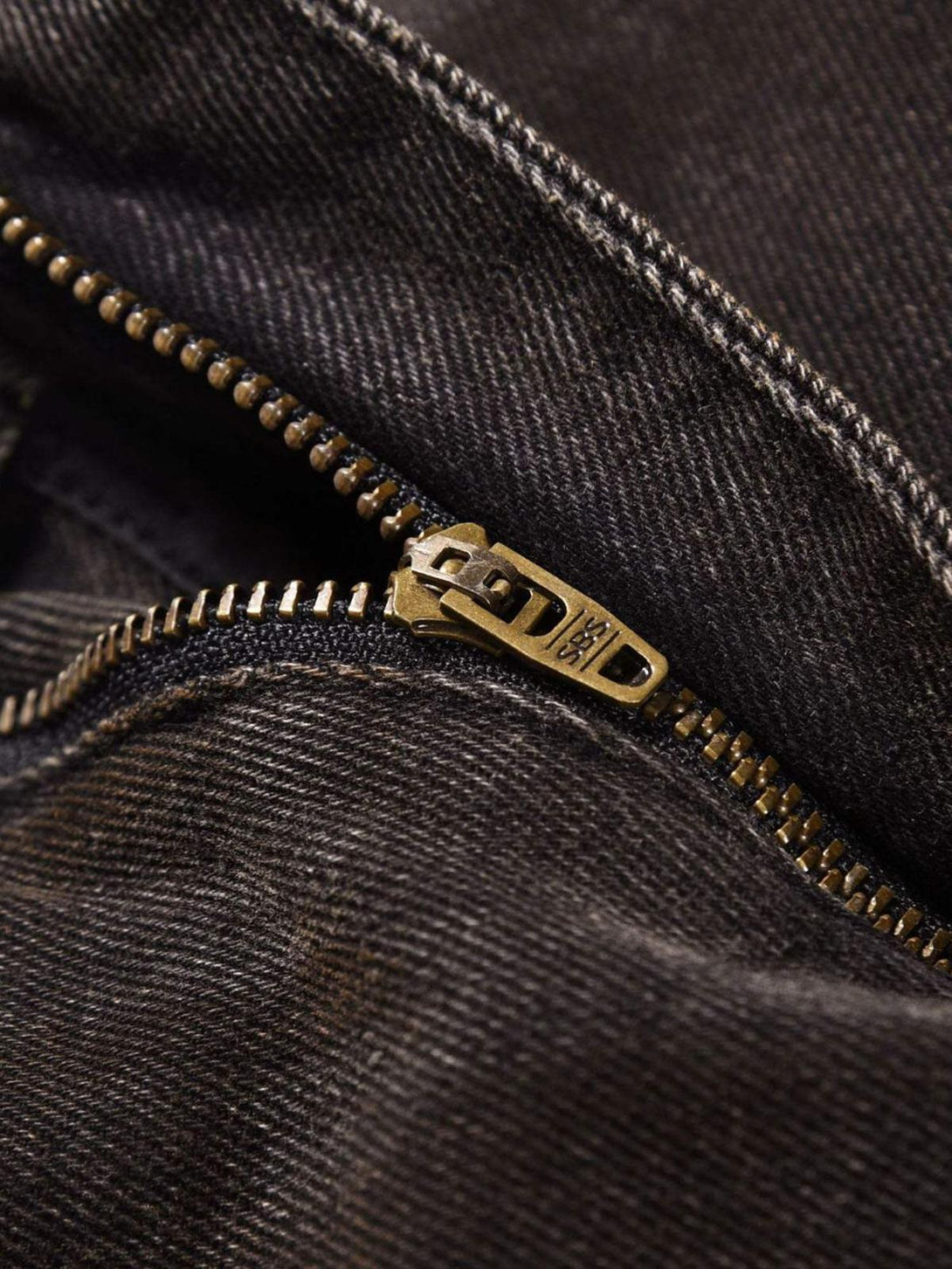Intricate look at TALISHKO's jeans zipper, highlighting rugged texture and industrial style.