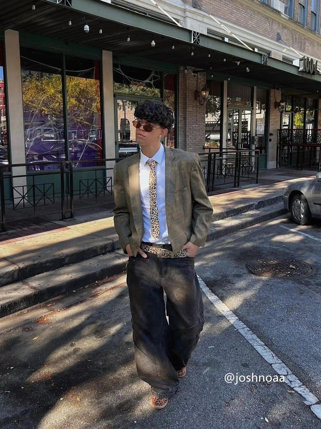 Model wearing washed jeans and blazer by TALISHKO, showcasing an urban street style.