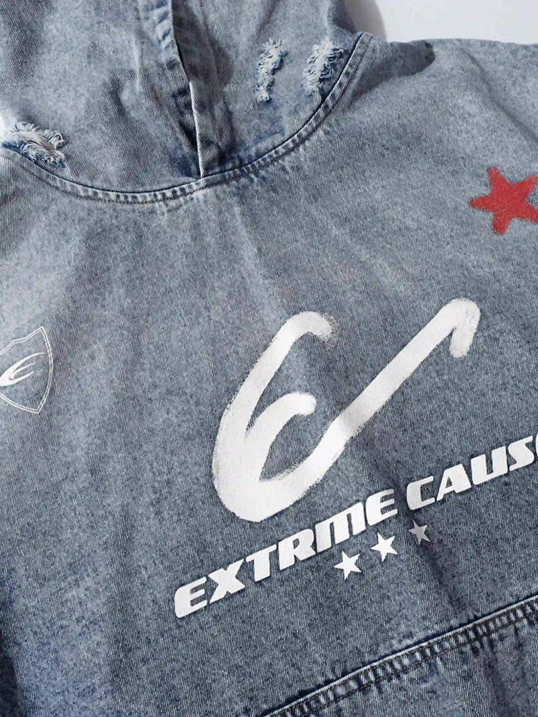 Close-up of TALISHKO's distressed denim hoodie, highlighting graphic details and texture.
